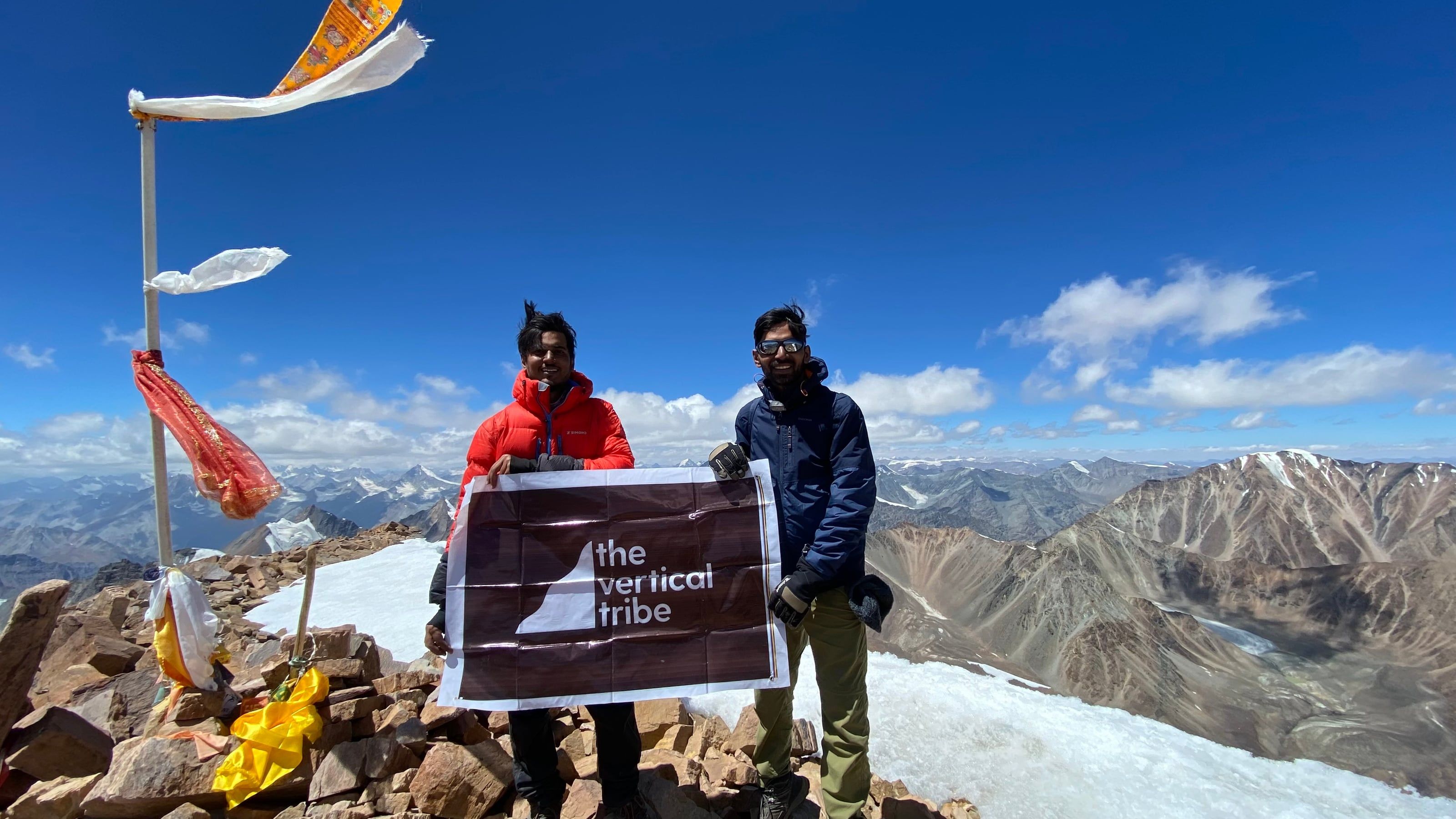 Two TVT climbers on the Yunam Peak summit holding the Vertical Tribe flag
